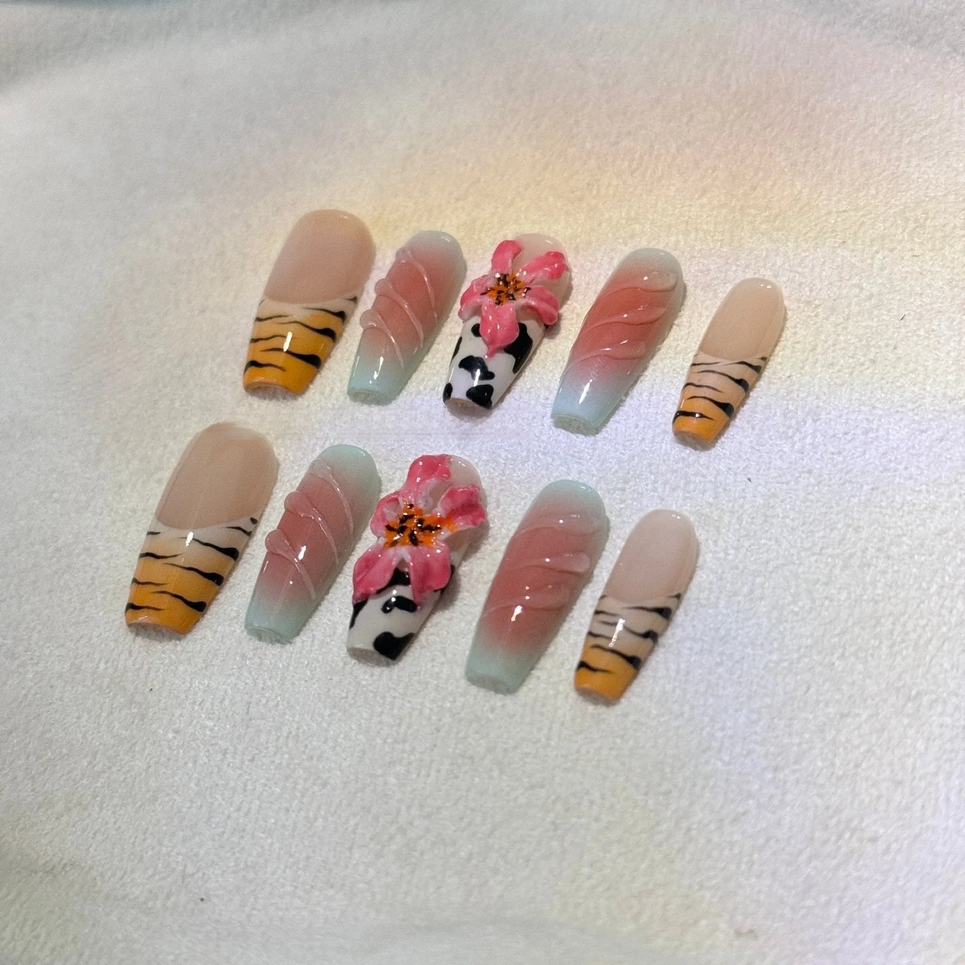 Zebra pattern and Lily hand carved nail art with flower and leopard print designs on a clear background.
