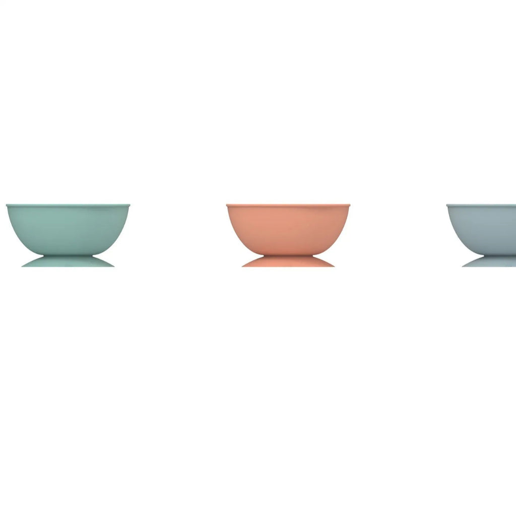 Cyan silicone pet licking mat and slow feeder bowl with suction cup base on a table.