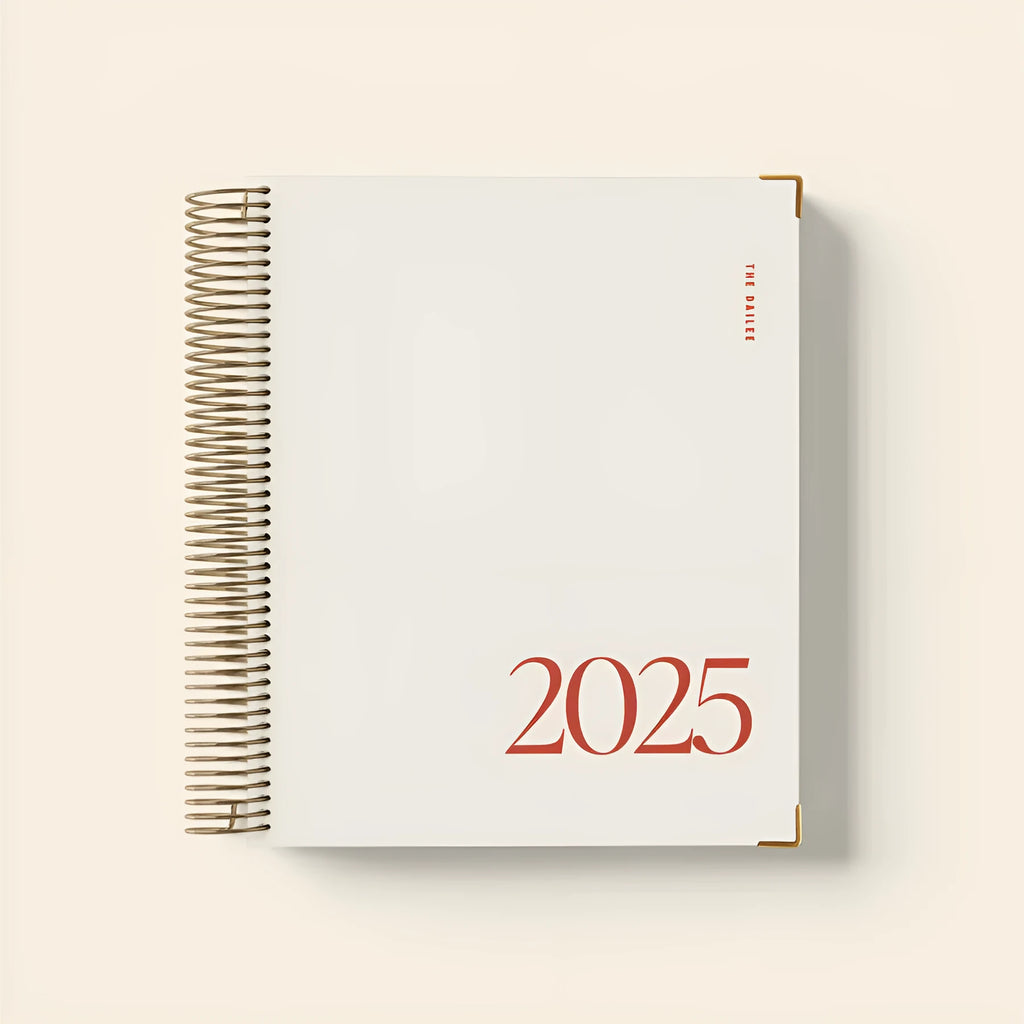 Cherry red coil-bound daily schedule notebook with wire-o binding lying open on surface