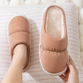 A pair of down cotton slippers with a thick rubber sole and artificial leather upper in a selected colour.