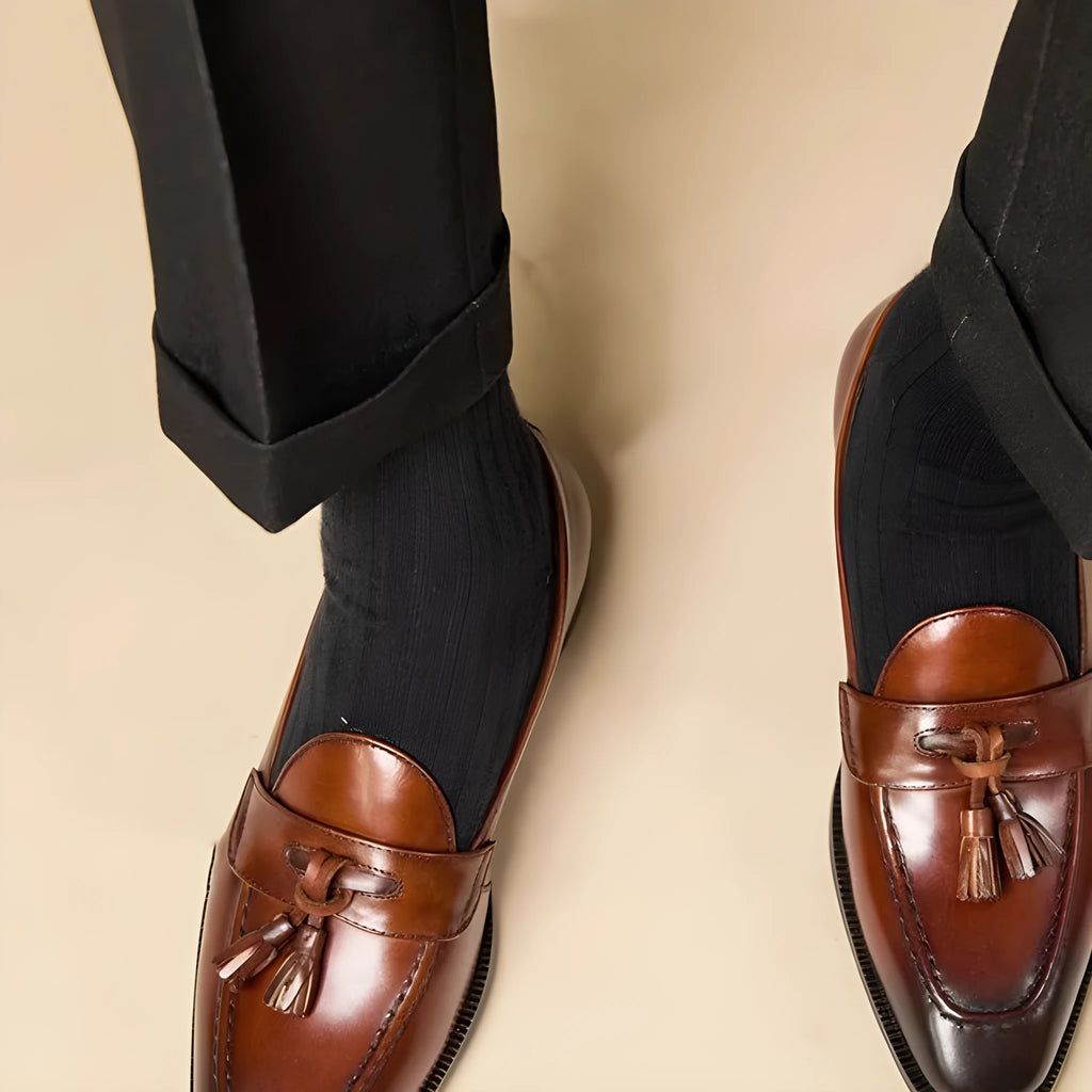 Men's black and brown genuine leather tassel loafers on a white background.