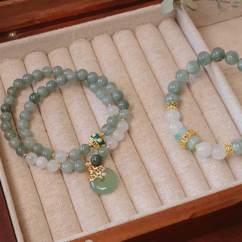 Close-up of a women's Myanmar jade bracelet with a traditional Chinese safety buckle pendant and geometric lucky bead charm.