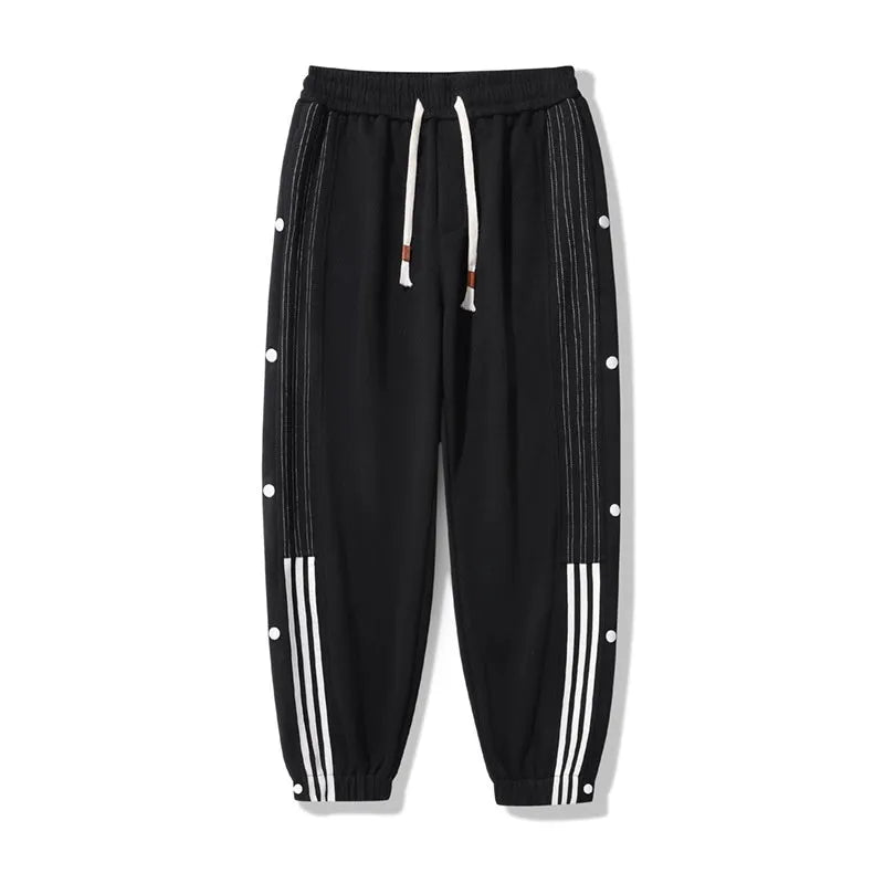 Man wearing black high-waisted, loose, ankle-tied sweatpants with a belt, showing the drawstring waist.
