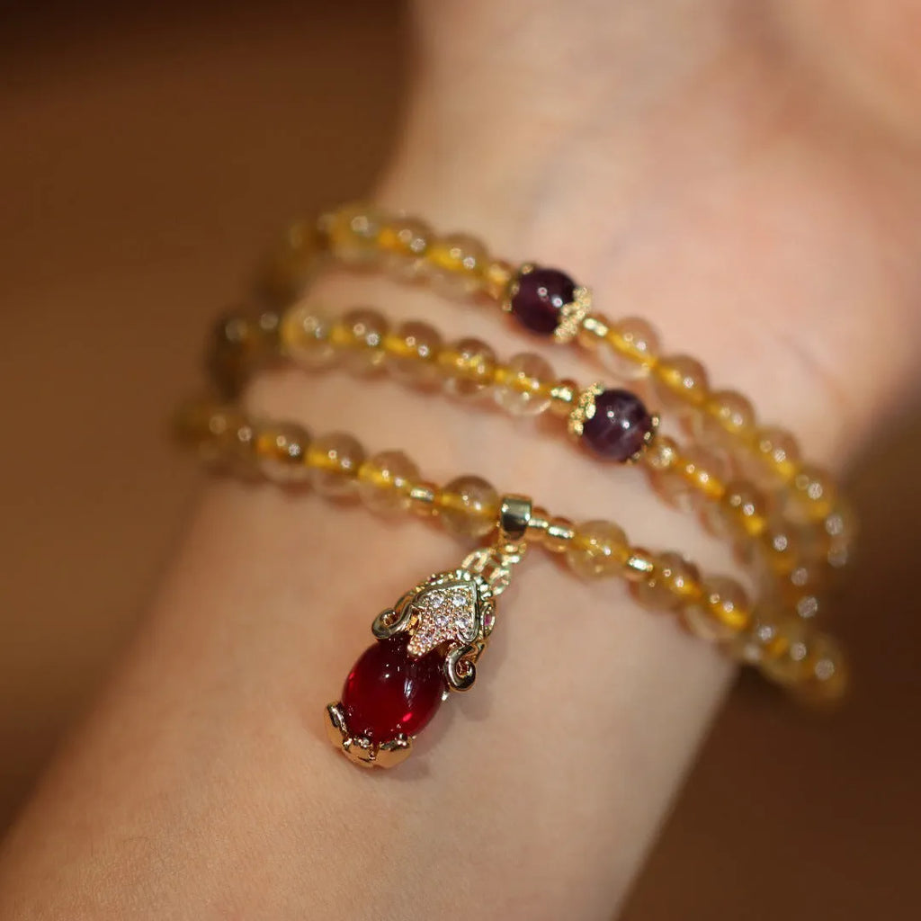 Handmade bracelet with Brazilian rutilated quartz beads, three gold circles, and a hanging bead pendant.