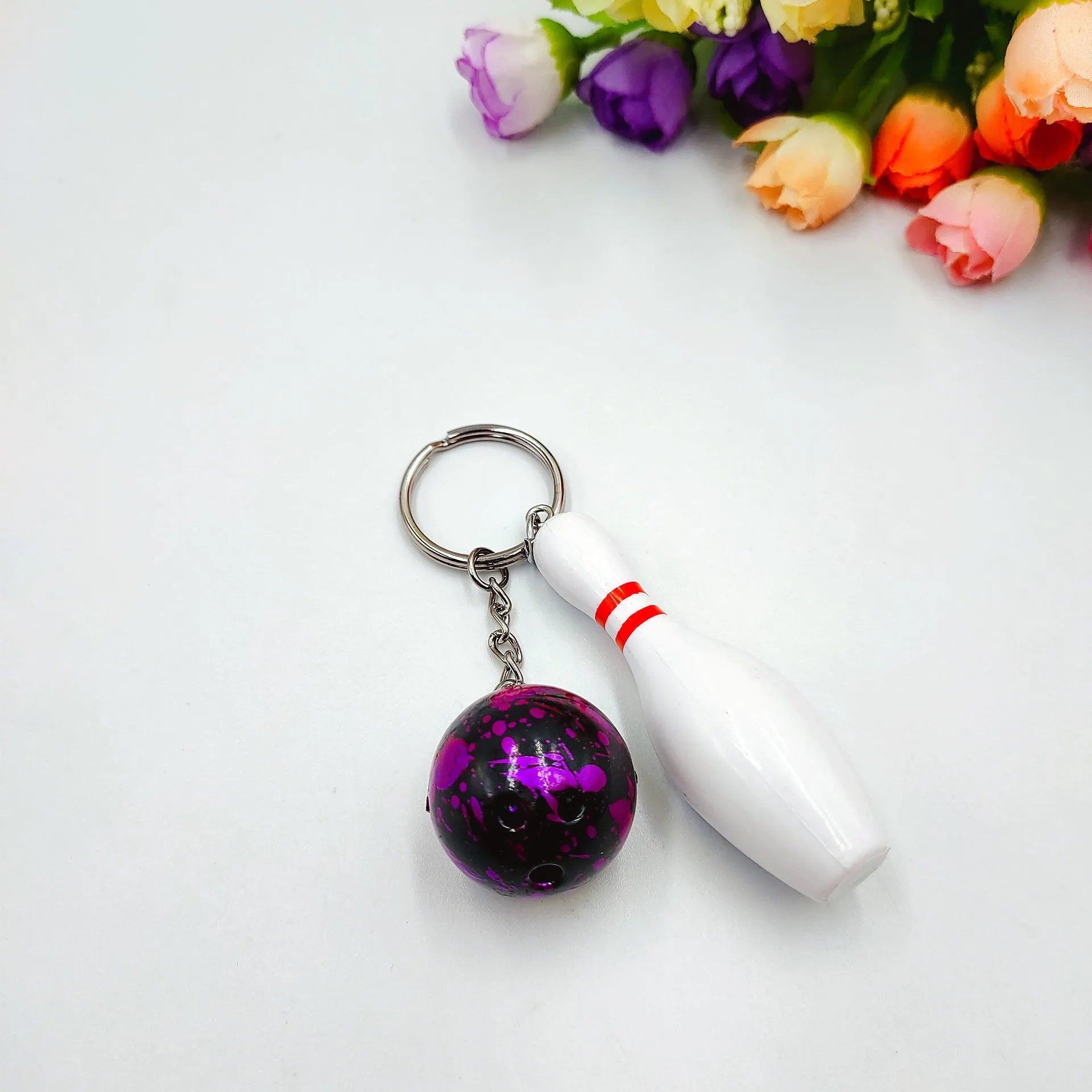 Miniature bowling ball keychain pendant in dark red, blue, purple, and green colours.
