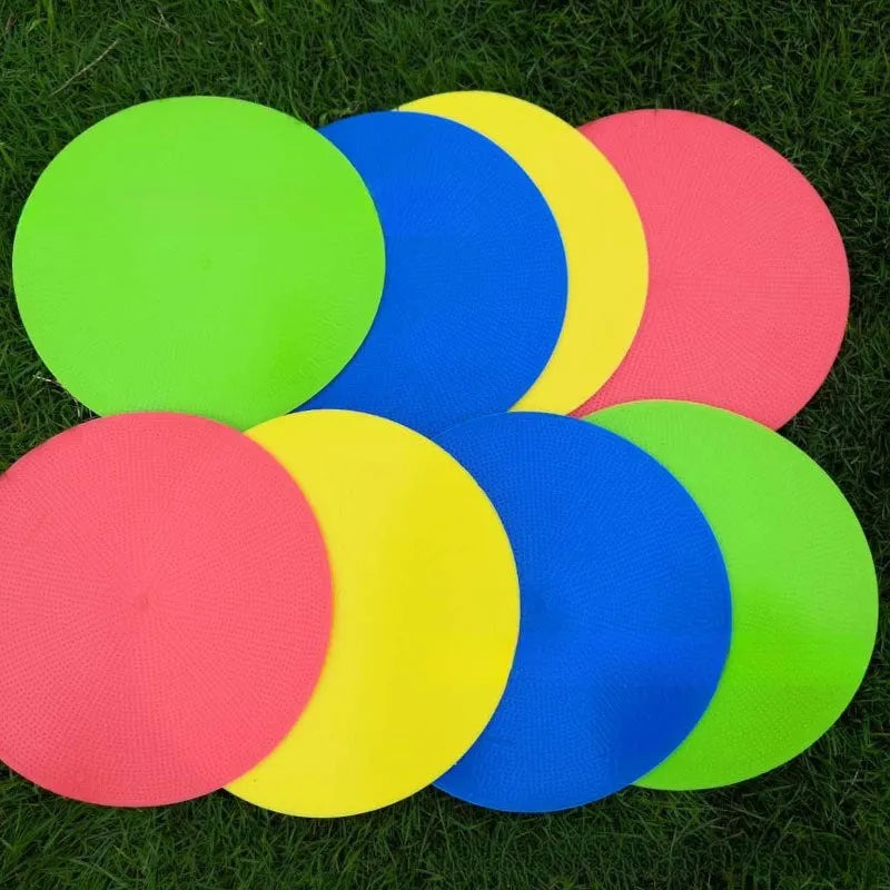 Yellow TPE football training marker disc lying flat on grass, 23cm diameter.