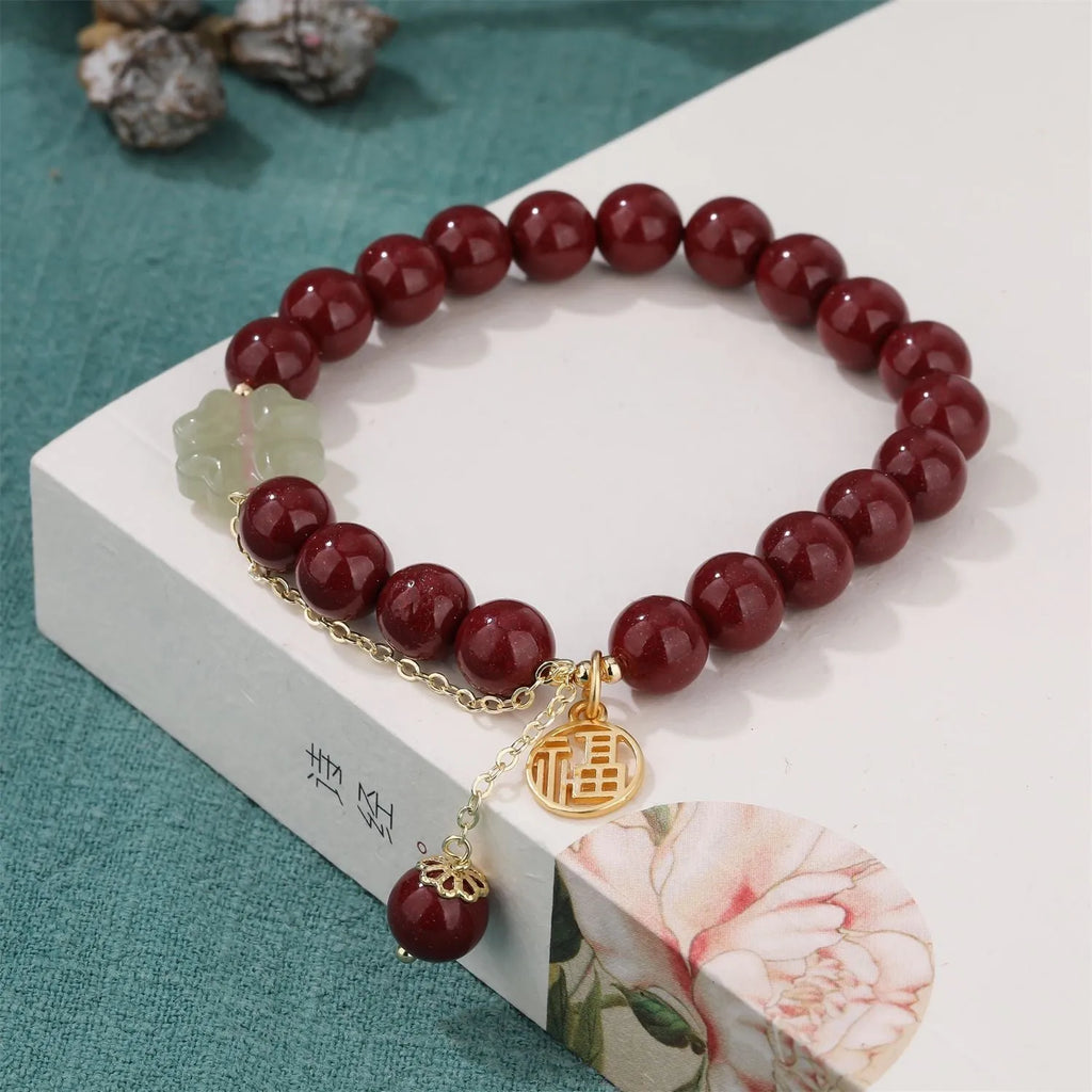 Close-up of a handmade purple gold sand cinnabar bracelet with a Fu character charm and peach blossom tassel.