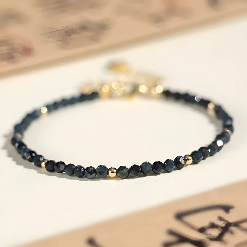 3mm blue tourmaline cut bead bracelet with gold spacer beads on wrist