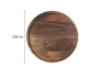 Solid black walnut wood cutting board with juice groove and side handle on a kitchen counter