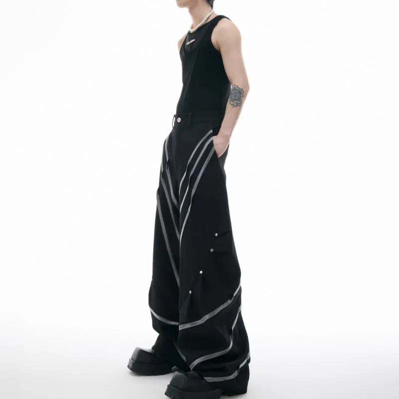 Men's black polyester trousers with metal striped rivets and pleated detail on a white background.