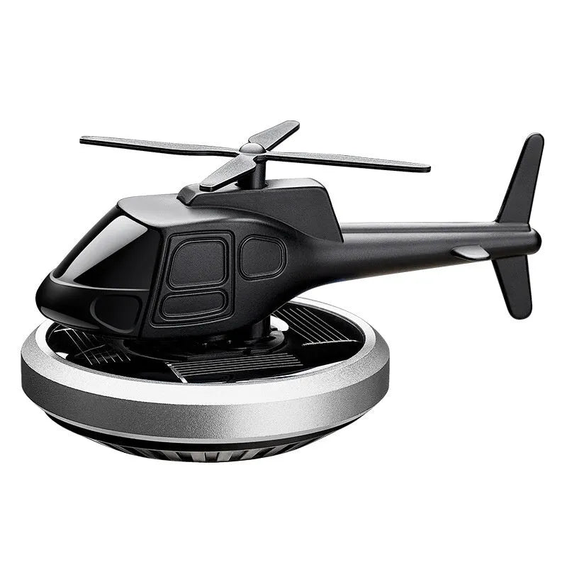 Metal solar helicopter car perfume ornament with rotating blades on a car dashboard.