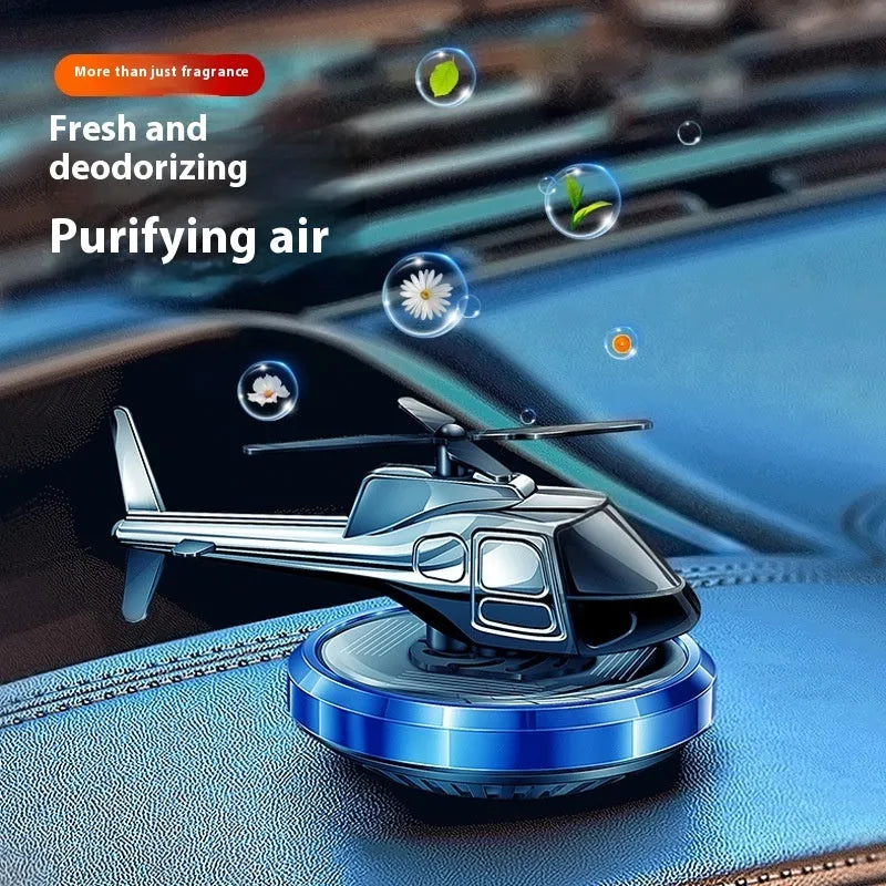 Metal solar helicopter car perfume ornament with rotating blades on a car dashboard.