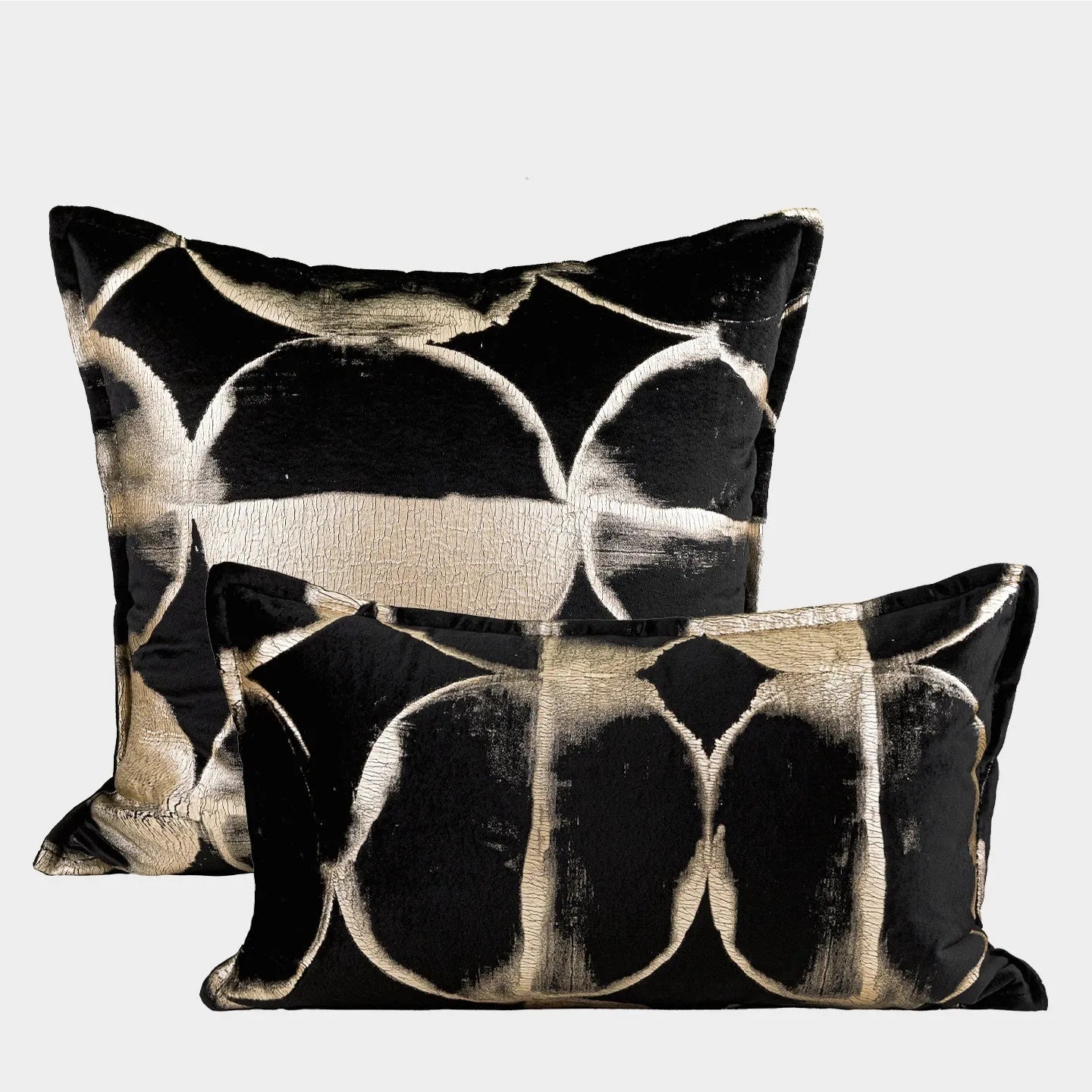 Black and gold abstract patterned square decorative pillow with a flannel cover on a grey sofa.