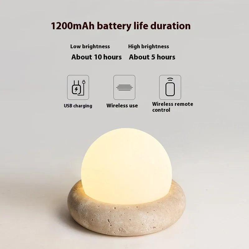 Cream-coloured modern bedside lamp with remote control on a table.