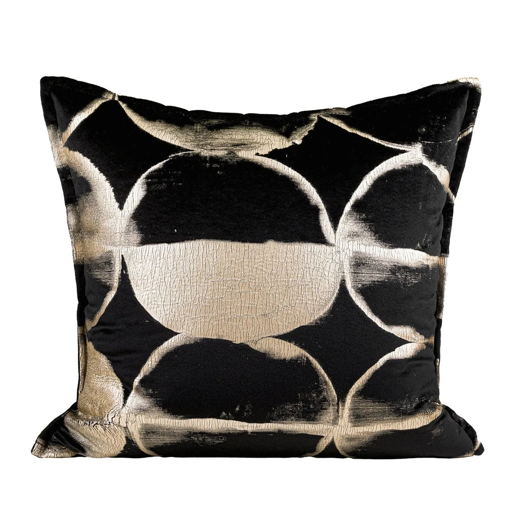 Black and gold abstract patterned square decorative pillow with a flannel cover on a grey sofa.