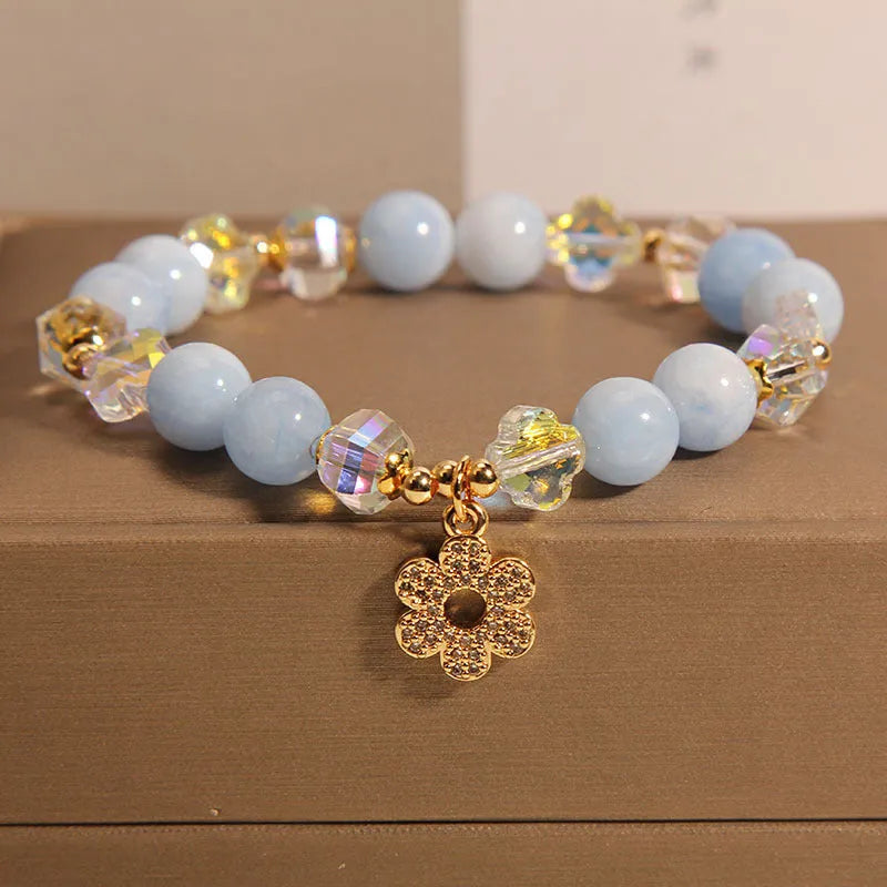 Women's aquamarine crystal bracelet with a four-leaf clover charm and pearl accents on a band.