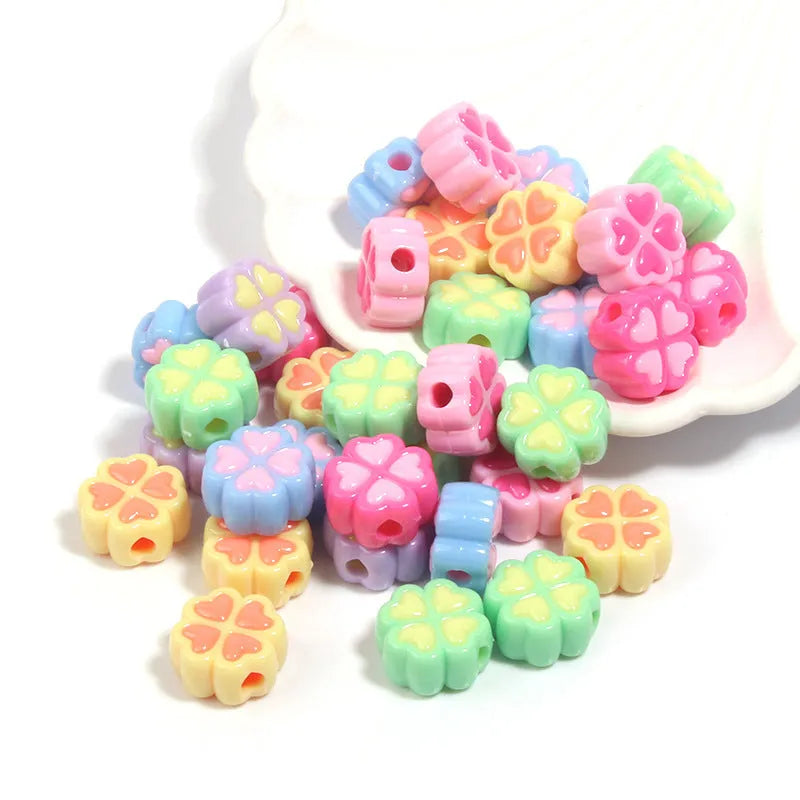Assortment of frosted acrylic love clover beads in mixed colours on a white background.