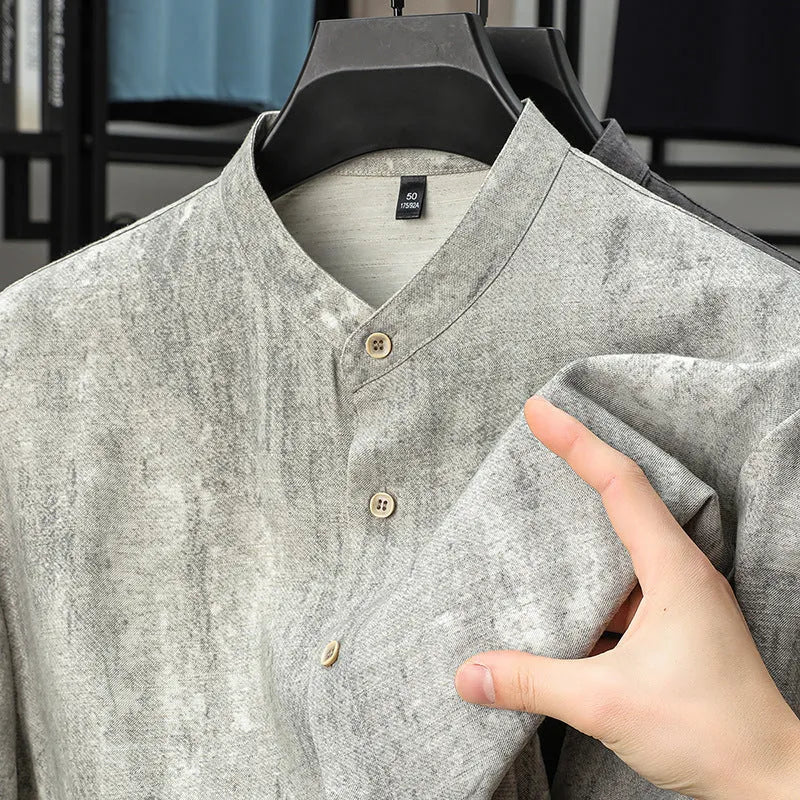 Man wearing a loose-fit black grey linen cardigan-style shirt with a stand collar and short sleeves.