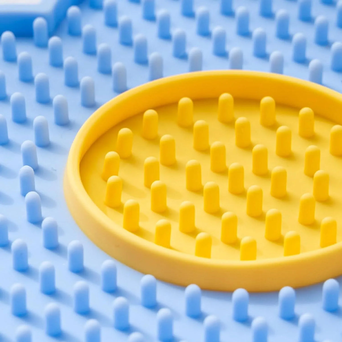 Flower-shaped silicone dog lick mat in pink with suction cups on the underside, shown on a tiled floor.