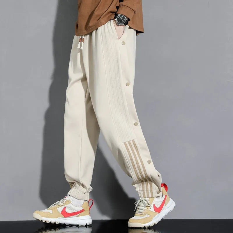 Man wearing black high-waisted, loose, ankle-tied sweatpants with a belt, showing the drawstring waist.