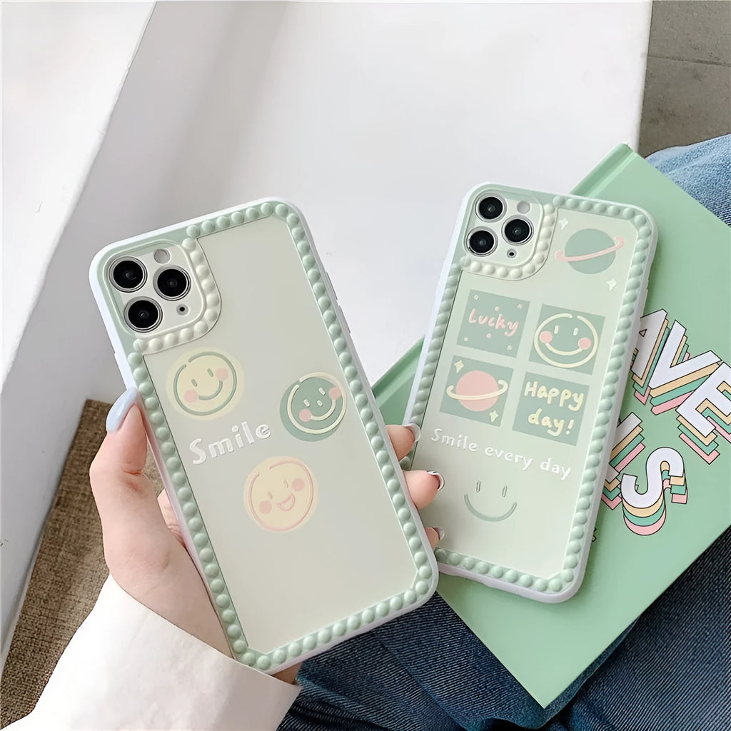 Green iPhone case with geometric smiley face pattern and polka dot border on a table.