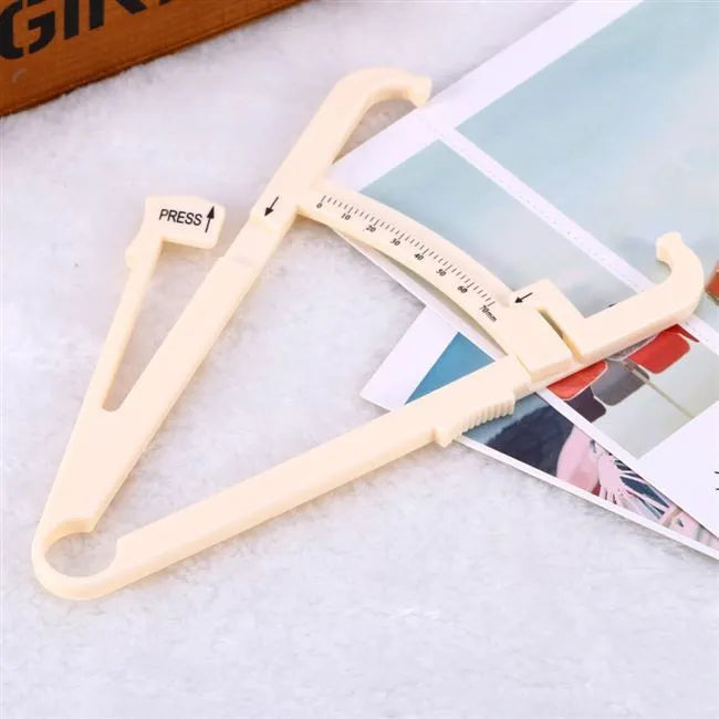 White acrylic body fat caliper skin fold thickness measuring tool on grey background.