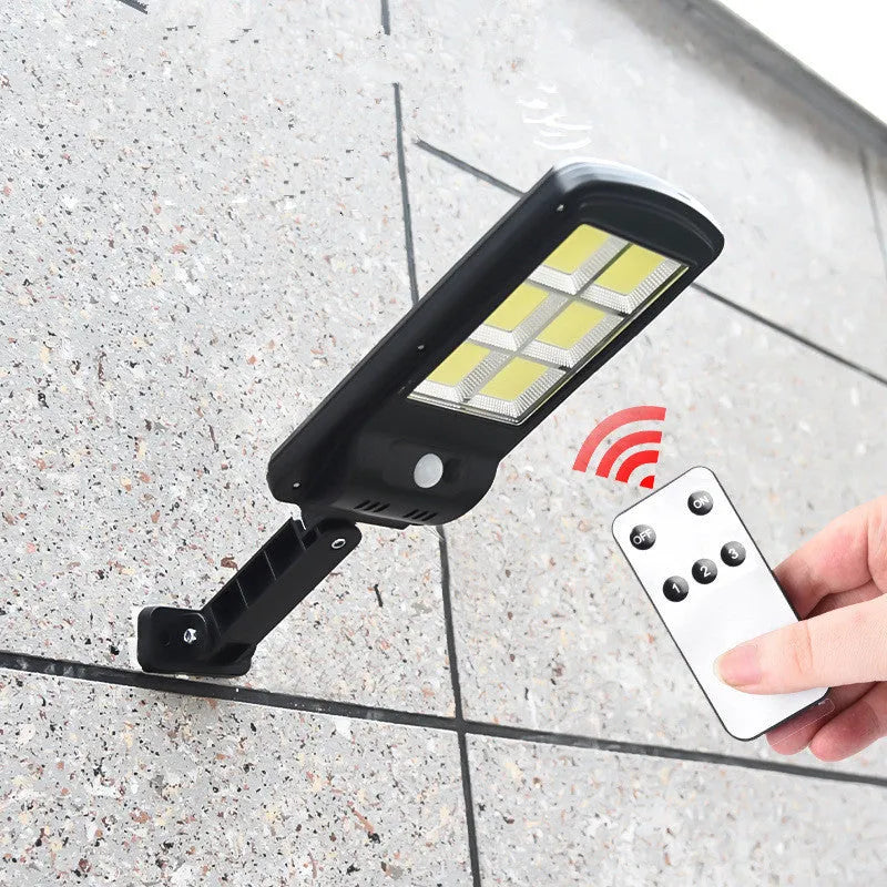 Black outdoor solar-powered motion sensor security light with solar panel on top.