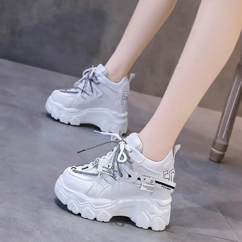 White women's low-top mesh sneakers with a black cross strap and a thick rubber platform sole.