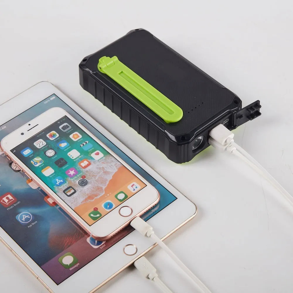 Green and orange portable solar hand crank power bank showing USB ports, solar panel, and hand crank