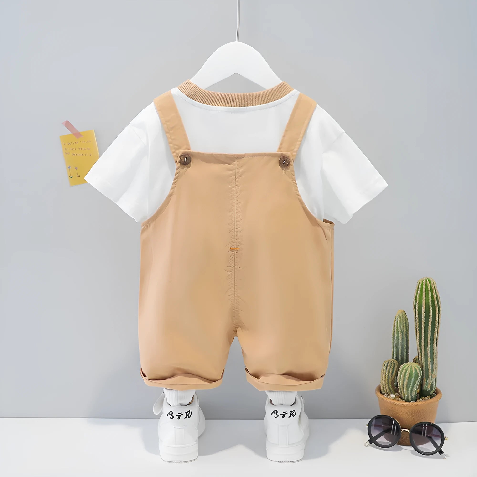 Baby wearing yellow cotton summer overalls with cartoon pattern and front buttons