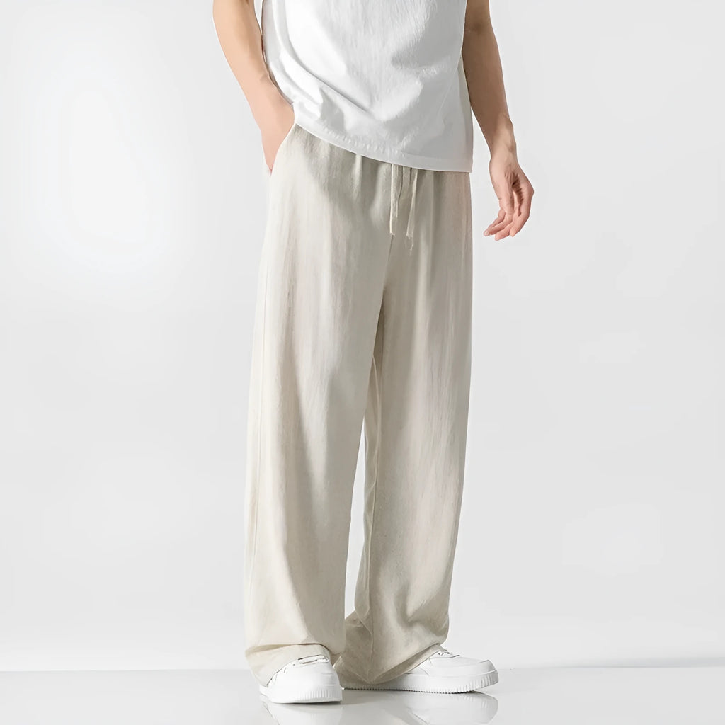 Man wearing beige straight-leg cropped linen trousers with a drawstring waist.