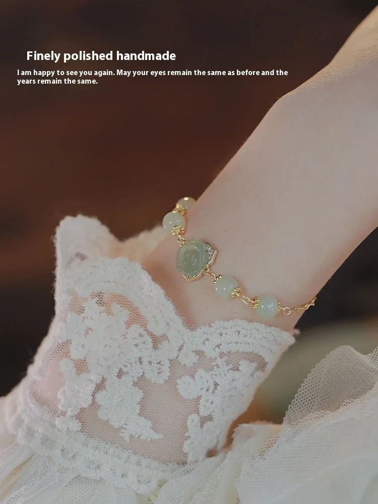 Close-up of a women's bracelet with a handmade Hetian Jade rose flower on a 14K gold plated band.