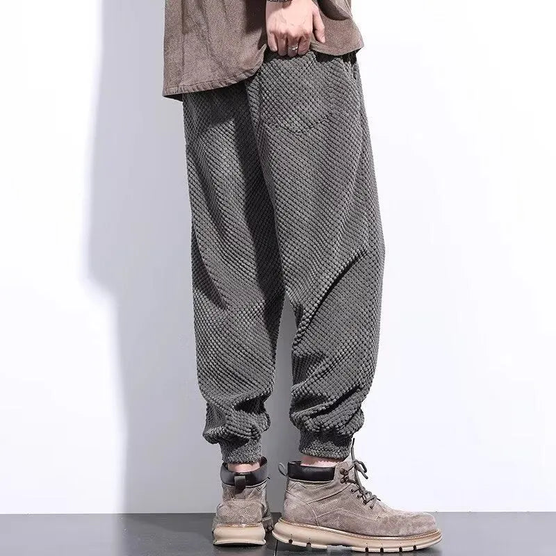 Man wearing grey straight-leg casual sweatpants with an ankle-tied design detail.