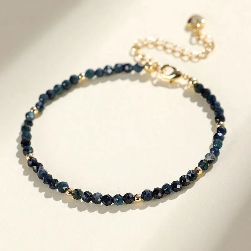 3mm blue tourmaline cut bead bracelet with gold spacer beads on wrist