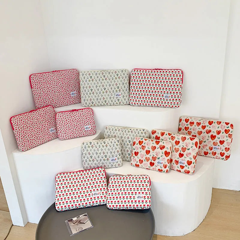 Printed cloth laptop bag showing floral and heart patterns in green, pink, and red colourways