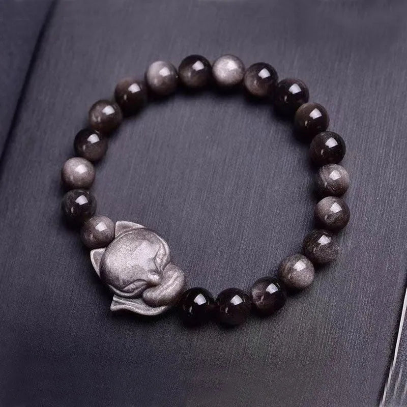 Close-up of a polished black obsidian bracelet bead carved with a detailed fox design.