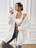 Women's dark green loose-fit mid-length acrylic cardigan sweater on a hanger.