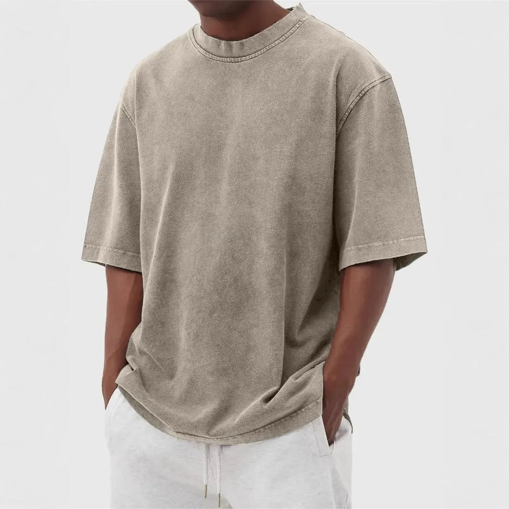 Man wearing a loose-fit, stone-washed distressed men's short sleeve T-shirt in a solid colour.