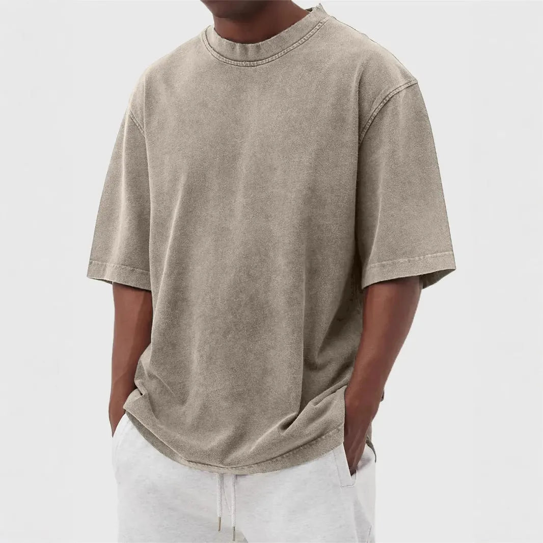 Man wearing a loose-fit, stone-washed distressed men's short sleeve T-shirt in a solid colour.
