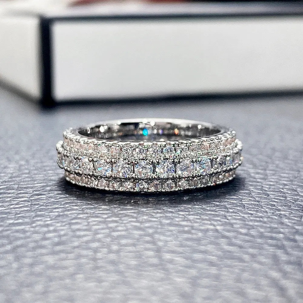 A geometric unisex ring with a triangular zircon stone inlay, shown in white gold, yellow gold and white and black plating finishes.