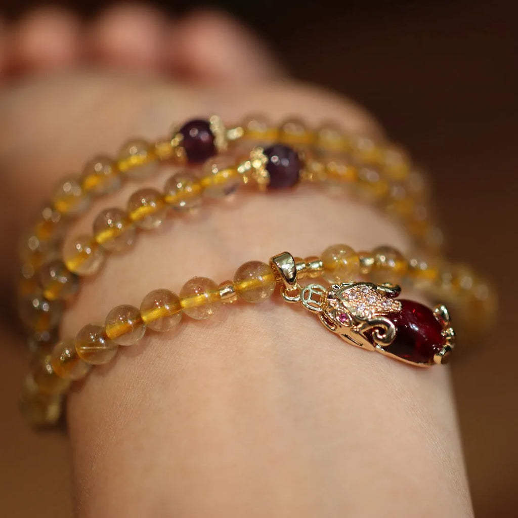 Handmade bracelet with Brazilian rutilated quartz beads, three gold circles, and a hanging bead pendant.
