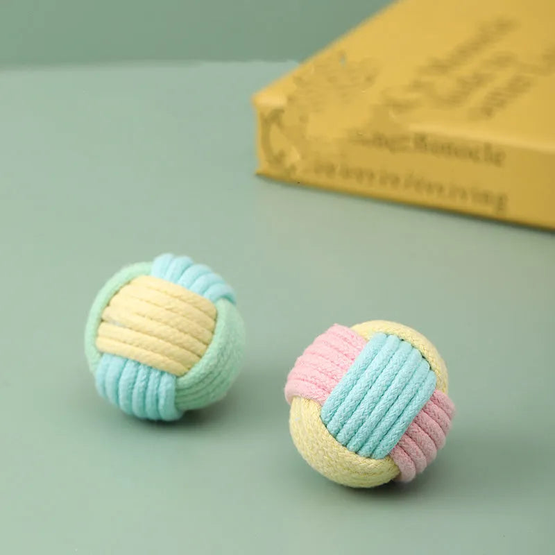 Four small handmade cotton plush balls for cats in assorted two-tone colours, shown next to a ruler for scale.