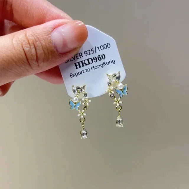Women's geometric heart-shaped earrings with rhinestones and a dangling tassel, shown in silver tone.
