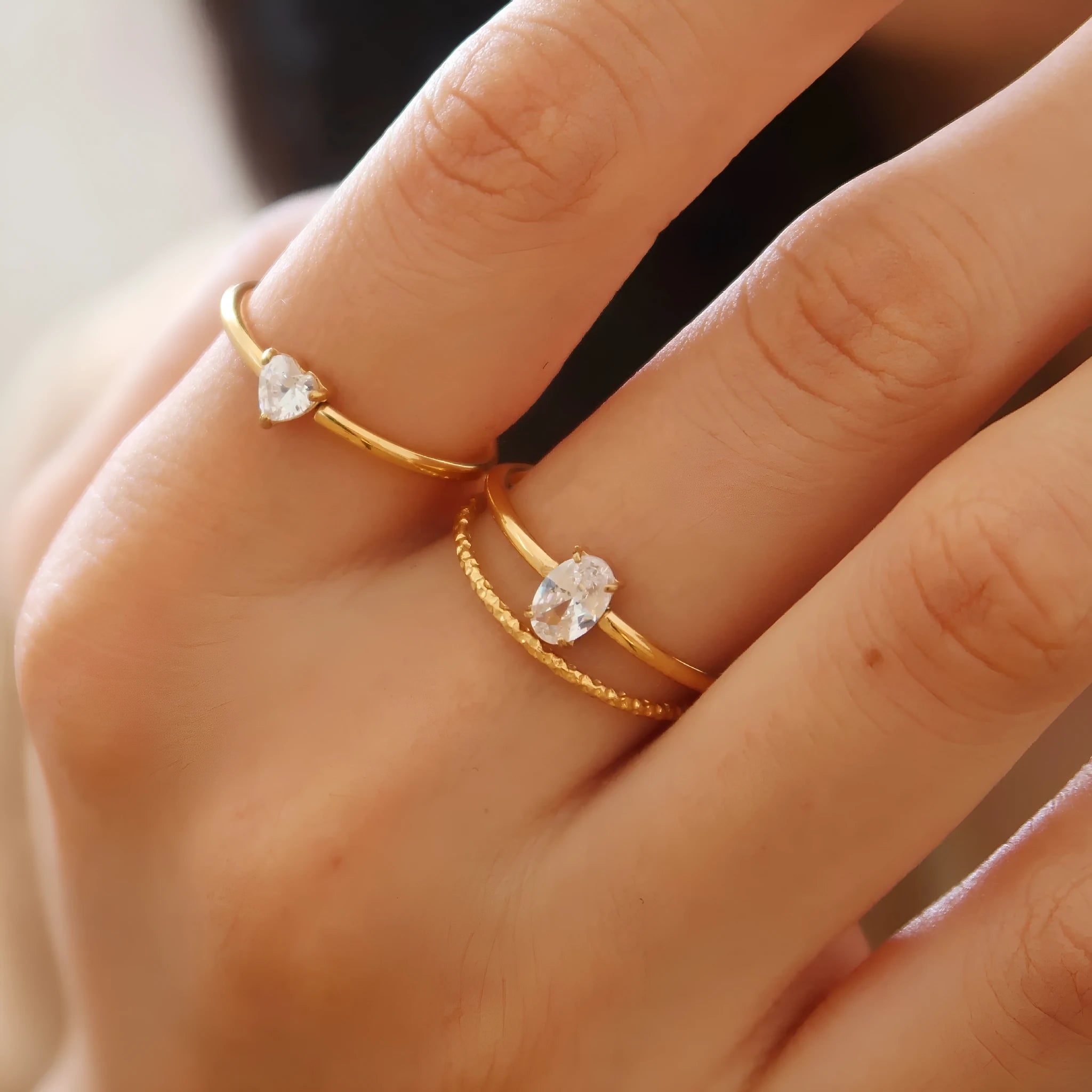 A golden stainless steel ring showing both the love heart design and the oval design option on a hand.