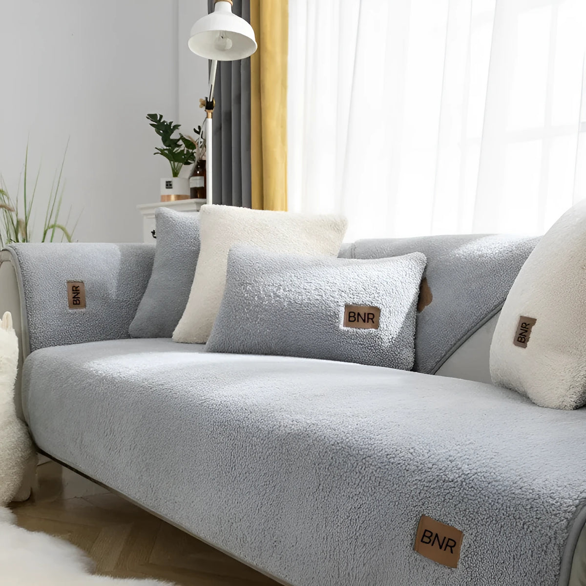 Lambswool solid colour sofa cover in blue, shown draped over a sofa arm.