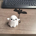 Small resin Halloween statue of a ghost walking a dog and holding a bat.