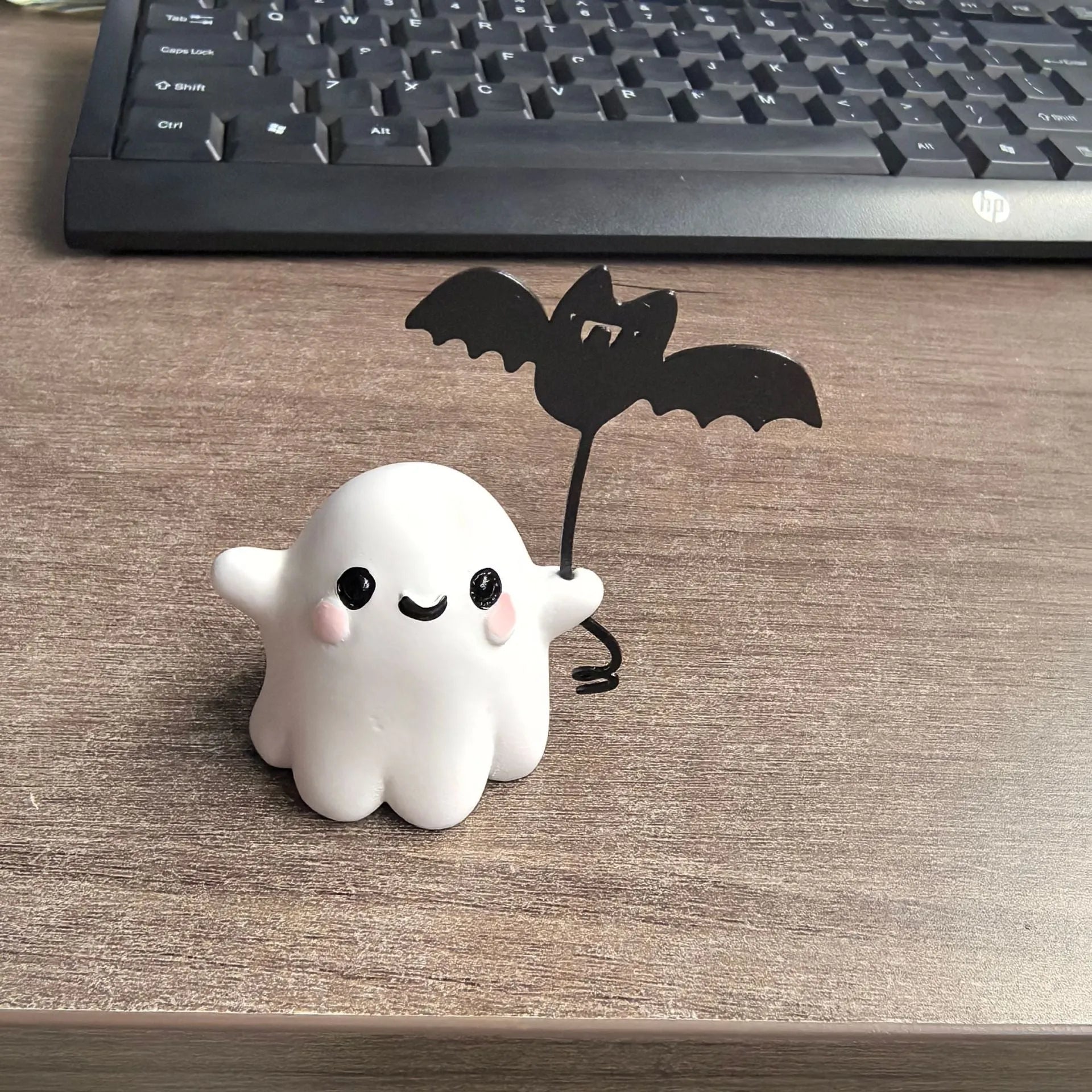 Small resin Halloween statue of a ghost walking a dog and holding a bat.