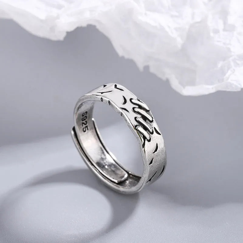 Black geometric copper ring with adjustable opening on a white background.