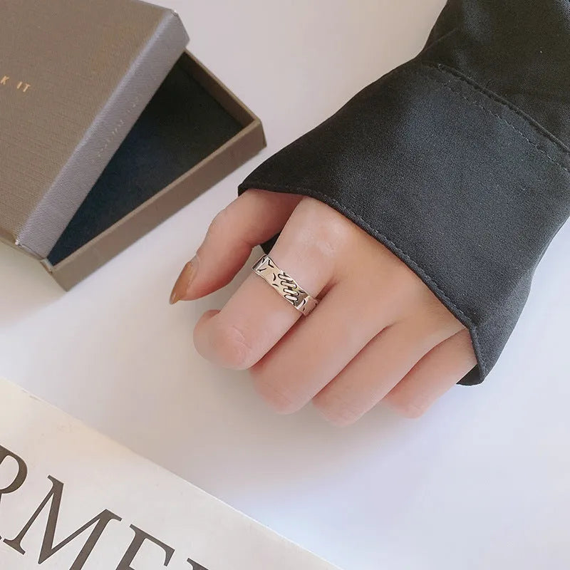 Black geometric copper ring with adjustable opening on a white background.