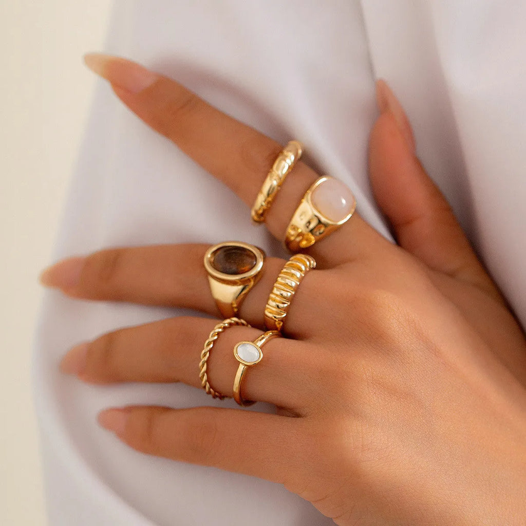 Six geometric alloy rings in light gold finish arranged for display